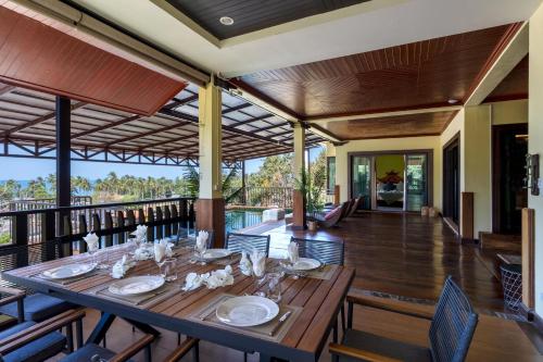 a long wooden table in a room with a balcony at 6 Bedrooms Seaview With Pool - Belle Sunset Villa in Ko Lanta