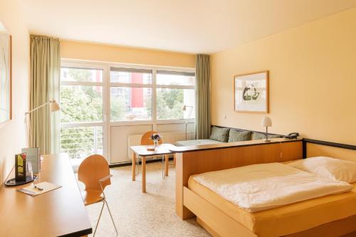 Schlafzimmer mit einem Bett, einem Schreibtisch und einem Fenster in der Unterkunft Hotel Am Weberplatz in Dresden