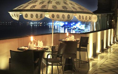 a patio with tables and chairs under an umbrella at BrijRama Palace, Varanasi - By the Ganges in Varanasi