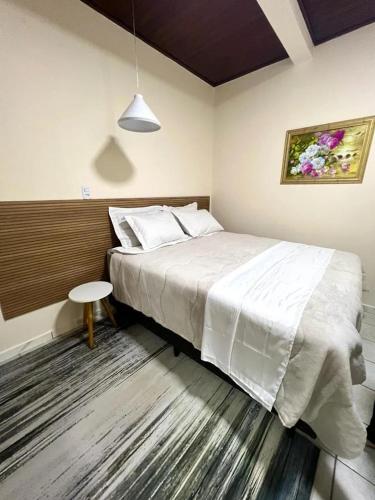 a bedroom with a large white bed and a table at Hotel Serrano in Inácio Martins