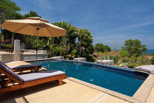 a swimming pool with a chair and an umbrella at Amazing Seaview Apartment in Ko Lanta