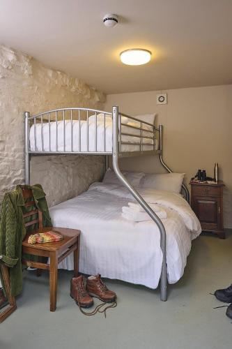 a bedroom with a bunk bed with a table and shoes at Drewe Arms Bunk Rooms in Drewsteignton