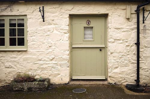 a stone building with a green door and a window at Drewe Arms Bunk Rooms in Drewsteignton