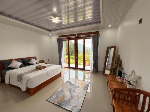 a bedroom with a bed and a large window at The Angga Kintamani in Kubupenlokan
