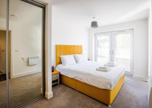 a bedroom with a large bed and a mirror at Comfortable modern apartment near Bicester in Bicester