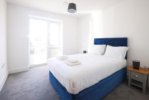 a bedroom with a blue and white bed with towels on it at Comfortable modern apartment near Bicester in Bicester