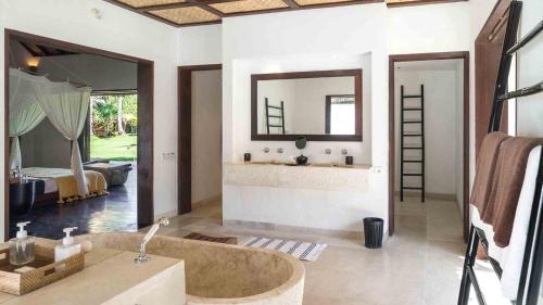a bathroom with a tub and a sink and a mirror at Luxury Beachfront Villa in North Lombok in Gili Islands