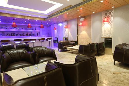 a restaurant with leather chairs and a bar with purple lighting at Clarks Inn Suites Gwalior in Gwalior