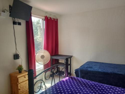 a bedroom with a bed and a window with red curtains at Casa en la Palpa in Huauchinango