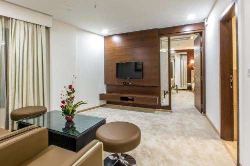 a hotel room with a television and a table and chairs at Clarks Inn Suites Gwalior in Gwalior