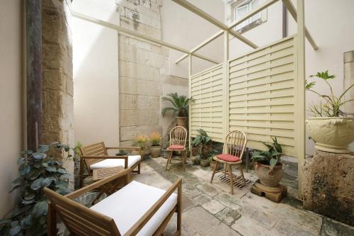 a patio with chairs and tables and plants at La Via della Giudecca in Syracuse