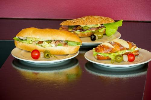 three plates with sandwiches on them on a table at Dasbreitehotel am Rhein in Basel