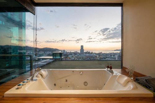 a bath tub in a room with a large window at The Senses Resort & Pool Villas, PHUKET in Patong Beach