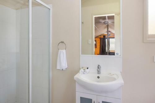 a white bathroom with a sink and a shower at Reflections Red Rock - Holiday Park in Red Rock