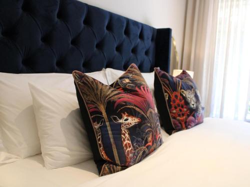 two pillows on a bed with a blue headboard at Oak Manor Boutique Guest House in Cape Town