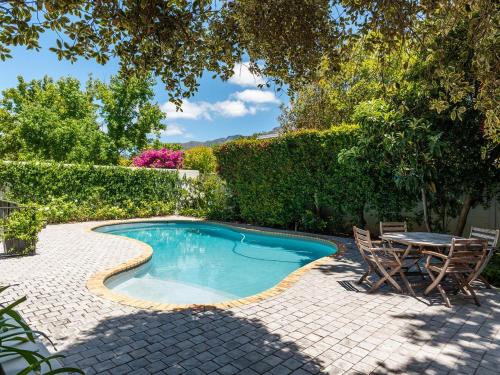 a swimming pool in a backyard with a table and chairs at Oak Manor Boutique Guest House in Cape Town