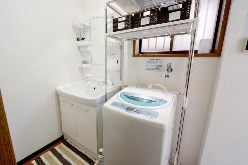 a small bathroom with a washing machine and a sink at 一隅居 in Yaochō