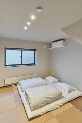 a bedroom with two beds and a window at Hotel GGG Asahikawa in Asahikawa