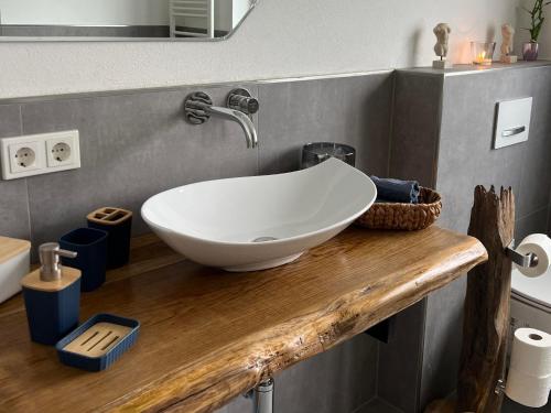 a bathroom with a white bowl sink on a wooden counter at Simply Enjoy Ferienwohnungen in Losheim
