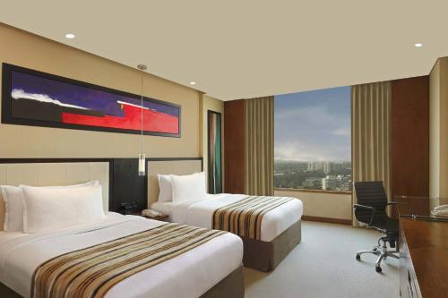 a hotel room with two beds and a large window at DoubleTree by Hilton-Pune Chinchwad in Pune