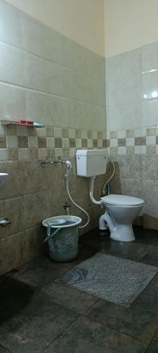 a bathroom with a toilet and a bucket at Chippy Residency Coorg in Gonikoppal
