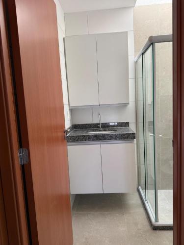 a white kitchen with a sink and a glass door at Casa condominio Carpe Diem in Marechal Deodoro