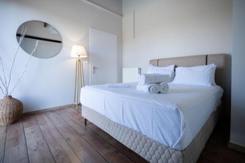 a bedroom with a large white bed with a mirror at Le petit luxury apartment in Preveza