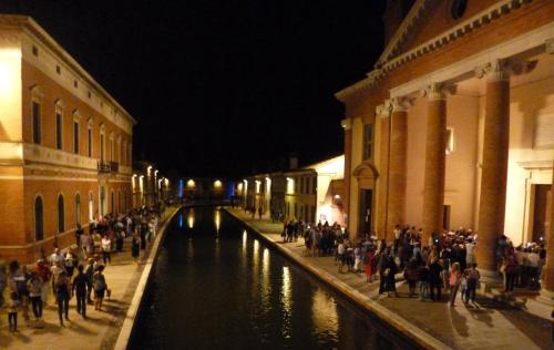 a group of people standing next to a canal at night at Villetta Botticelli in Lido di Spina