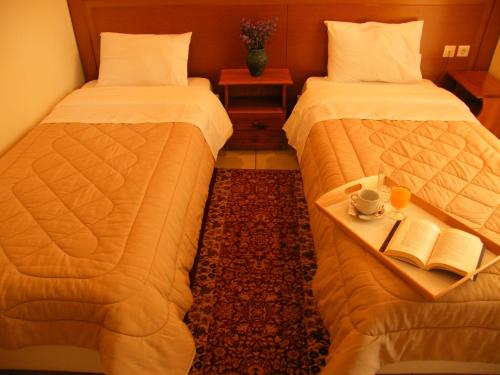 a hotel room with two beds and a tray with a book at Ξενοδοχείο Αφροδίτη- Hotel Aphrodite in Nafpaktos