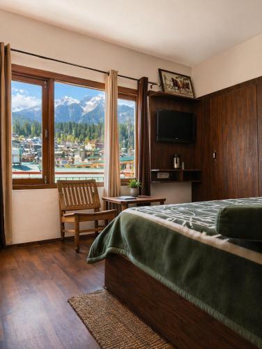 a bedroom with a bed and a large window at Hotel Premier in Manāli