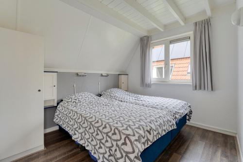 a white bedroom with a bed and a window at Groene Specht 16 in Gramsbergen