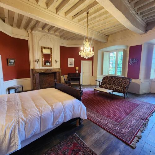 a bedroom with a bed and a couch and a fireplace at Château de Trévien in Trévien