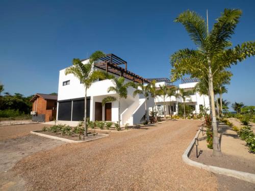 a white building with palm trees in front of it at Casa Norte – Oceanfront Villa in Placencia