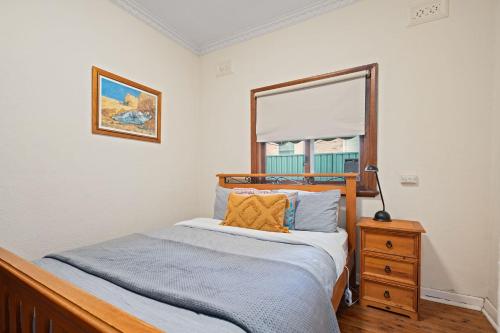 a bedroom with a bed and a dresser and a window at Red Brick Beauty - Central Cottage in Albury