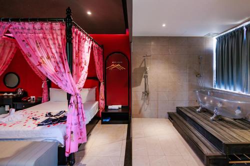 a bedroom with a tub and a bed with pink curtains at Tina 5 hotel cần thơ in Ấp Phú Thạnh (4)