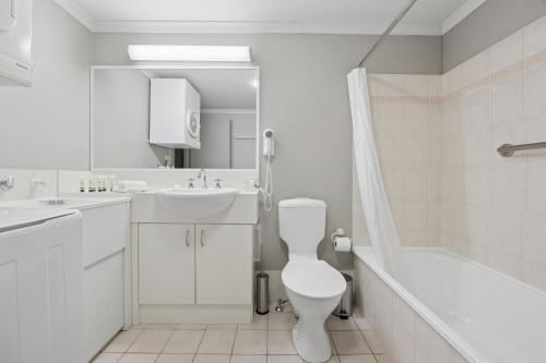 a white bathroom with a toilet and a sink and a tub at Horizons 302 in Jindabyne