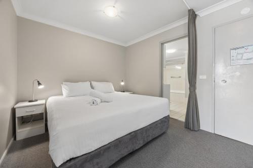 a white bedroom with a large bed and a shower at Horizons 302 in Jindabyne