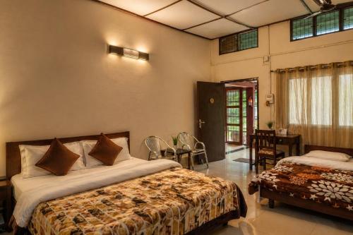 ein Schlafzimmer mit zwei Betten, einem Tisch und Stühlen in der Unterkunft Bononi in Jorhat