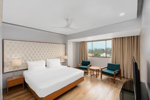a hotel room with a bed and two chairs at Classic Grande,a Member of Radisson in Imphal