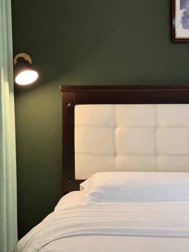 a bedroom with a white bed and a green wall at Mansion Inn Sibu in Sibu