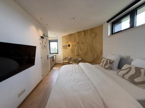 a bedroom with a large white bed and a television at Wasserturm Hotel Elsenborn in Butgenbach