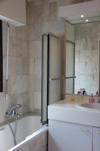 une salle de bain avec une baignoire, un lavabo et un miroir dans l'établissement Central avec Jardin, à Cannes