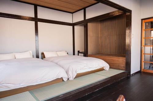 two beds in a room with a shower at 白灯-Hakuto- Ishiuchi in Minami Uonuma