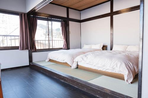 a bedroom with a bed and two windows at 白灯-Hakuto- Ishiuchi in Minami Uonuma