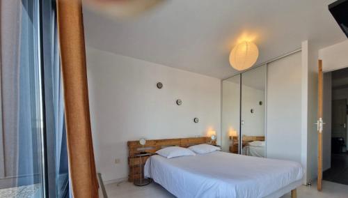 a bedroom with a white bed and a mirror at Fasthotel L'Eldorado in Sébazac-Concourès
