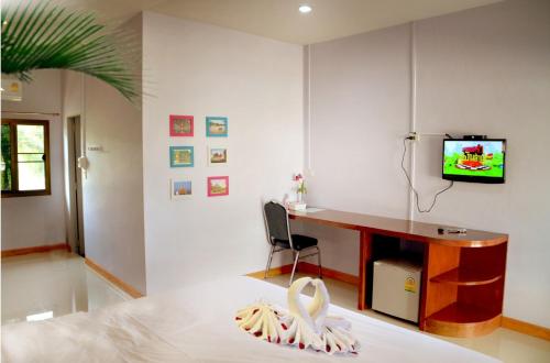 a bedroom with a desk and a tv on a wall at Chao Phraya Home in Ban Bon