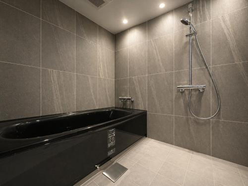 a bathroom with a black tub and a shower at Randor Hotel Sapporo Heritage in Sapporo