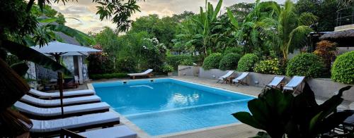 a swimming pool in a backyard with chairs and a table at Maison Carrée Andilana in Andilana