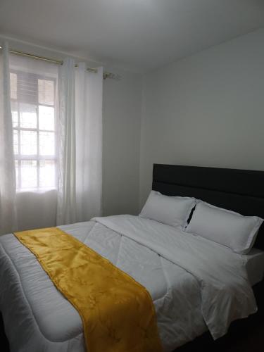 a bedroom with a bed with a yellow blanket on it at Zariah Homes 2BR in Kakamega