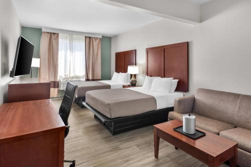 a hotel room with two beds and a couch at Quality Suites Waldorf in Waldorf
